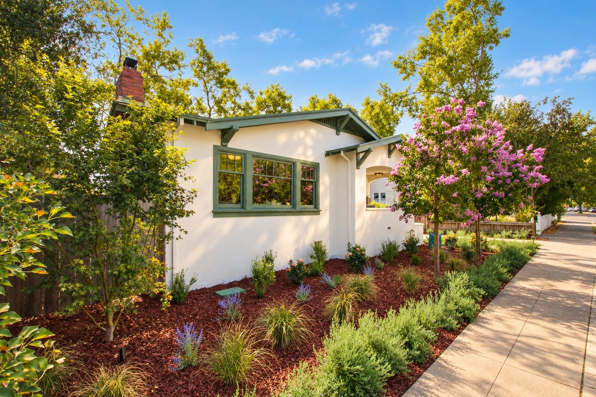 Adams Street white stucco home with green trim and a flowering front garden