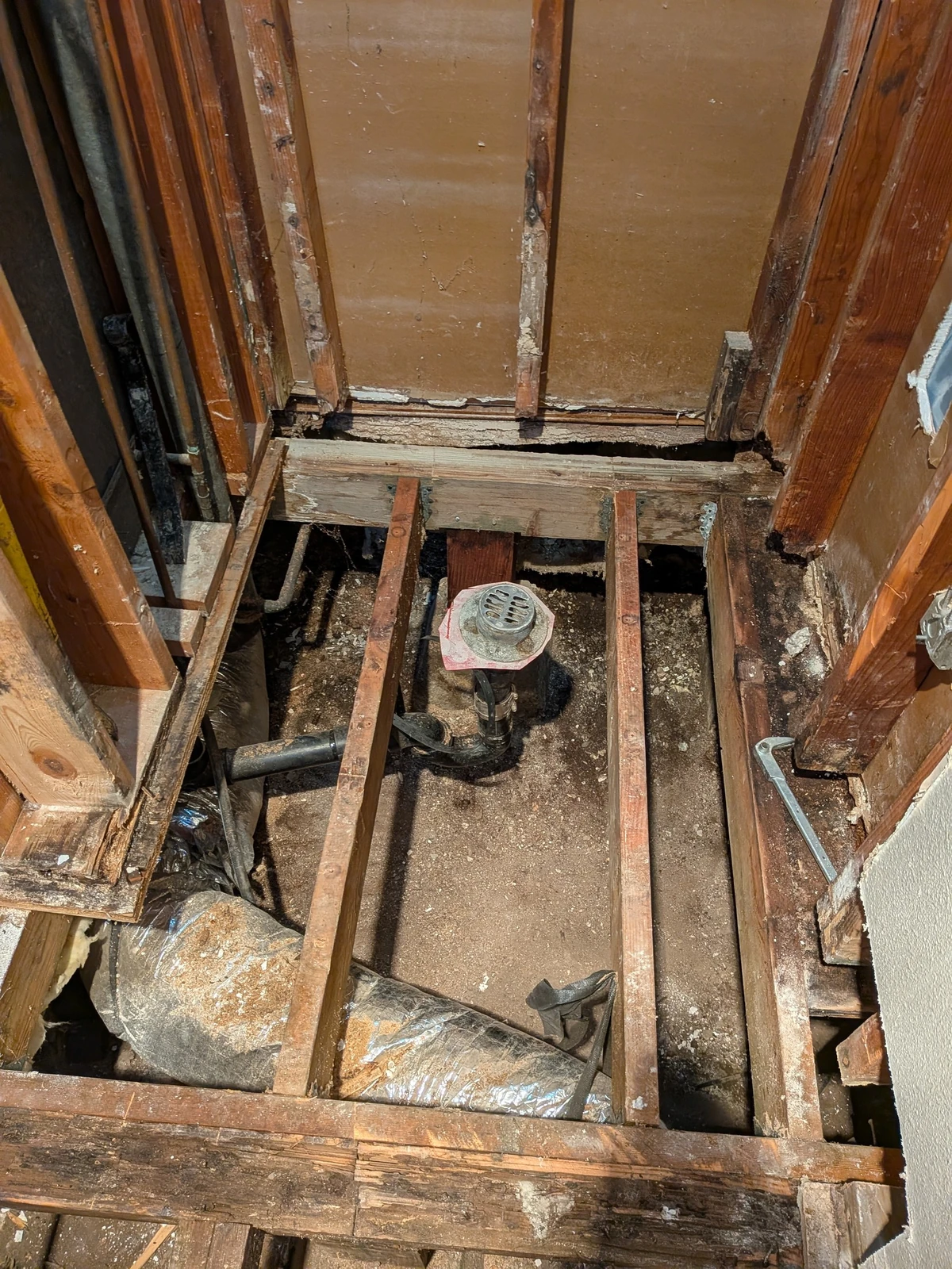Exposed wall framing, floor joists and plumbing during the Olive Street bathroom remodel